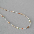 Dettaglio di perline colorate e perle bianche barocche su una collana girocollo fine - Bianco