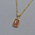 Close-up of gold-plated brass necklace with rectangular orange gemstone pendant - Pink Strawberry
