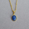 Detailed close-up of a gold necklace with a smooth oval blue gemstone and small gold beads - Blue Aventurine