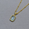 Macro detail of gold-plated brass necklace with a rectangular blue gemstone pendant - Aquamarine