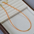 Detalle del collar de cuentas naranjas con colgante de pez koi dorado en una bandeja - Estilo Pez Koi (Collar)