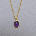 Macro shot of gold oval necklace featuring a purple stone pendant on a beaded chain - Purple Crystal