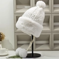 Detail of white chunky knit winter hat featuring faux fur trim and fluffy pom-pom accents - One Size / White