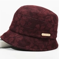 Detail shot of a dark burgundy cloche hat featuring embossed floral textures and gold plaque - One Size 58cm / Bucket Hat Red