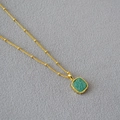 Macro detail of geometric square green stone pendant on golden beaded chain necklace - Amazonite