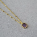 Detail einer vergoldeten Kugelkette mit einem quadratischen violetten Halbedelstein - Amethyst