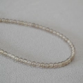 Vue macro de perles d'agate gris fumé translucides sur un collier minimaliste - 4mm