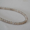 Gros plan sur les perles d'agate gris fumé translucides avec une surface polie sur tissu - 6mm