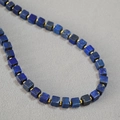 Detailed close-up of blue lapis lazuli cube beads with golden ring spacers on a necklace - Blue