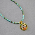 Gros plan détaillé d'un collier de perles fait main avec pendentif fleur et papillon émaillé - Orchidée de Juillet