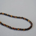 Dettaglio macro di perle naturali in occhio di tigre in colori misti per collana vintage - 4mm
