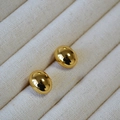 Polierte vergoldete ovale Ohrstecker für Damen auf einem minimalistischen Schmuckdisplay - Gold