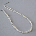 Dettaglio della collana a doppio strato con perle barocche e perline bianche su tessuto - Bianco