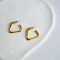 Macro shot of minimalist gold plated geometric trapezoid earrings on a ceramic display tray - Gold Geometric Trapezoid Style (2)