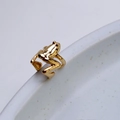 Macro shot of a detailed gold-plated frog ear cuff resting on a ceramic dish edge - Bright Gold Frog Shape Ear Cuff (7)