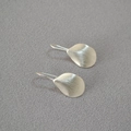 Pendientes minimalistas de pétalos plateados con textura cepillada vistos desde arriba - Plateado Cepillado