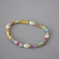 Dettaglio di collana colorata in stile boho con conchiglie e perle su tessuto strutturato - Serie di Colori del Braccialetto 1