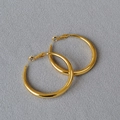 Makro-Detail von großen goldenen Creolen mit Hochglanz-Finish auf grauem Stoffhintergrund - 4cm / Gold