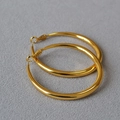 Makroaufnahme großer polierter Goldreifenohrringe mit glänzendem Finish und runder Form - 5cm / Gold