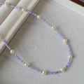 Detalle del collar con cuentas púrpuras facetadas, perlas blancas y bolas de oro fino - Morado
