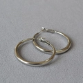 Detailaufnahme von polierten silbernen Oversize-Creolen mit glattem Metallfinish - 4cm / Weißgold