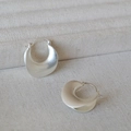 Makro-Detail silberner minimalistischer Creolen mit mattem Finish und Textur - Silber