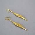Detail of long gold leaf earrings with textured finish and sparkling zircon accents - Gold Leaf Style