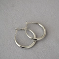 Detailed close-up of polished thick silver hoop earrings on a textured gray background - 3cm / White Gold