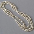 Elegante collana lunga di perle multistrato con perle di diverse dimensioni su grigio - Catena da maglione