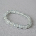 Macro shot of irregular light blue translucent natural stone beads on a textured fabric - Gray Blue