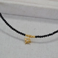 Detailed view of a black beaded necklace featuring a gold star pendant with a center crystal - Star Style