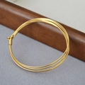 Détail d'un bracelet triple chaîne serpent plaqué or au design minimaliste moderne - Doré