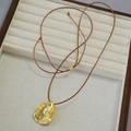 Minimalistische gouden lava-hanger ketting met verstelbaar bruin koord op een juwelentray - Bruin Koord