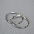 Detailed view of large polished silver C-shaped hoop earrings on gray fabric - Platinum 4cm