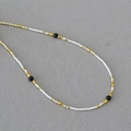 Collana minimalista con perline bianche Miyuki e onice nero su sfondo di tessuto grigio - Bianco (Onice Nero)