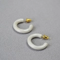 Dettaglio di orecchini a cerchio a C in resina marmorizzata con perni in argento 925 dorato - Bianco