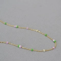 Close-up of thin gold-plated brass chain with colorful geometric square stone beads - Purple White and Green