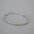 Macro shot of thin bohemian beaded bracelet with grey faceted stones and a gold bead accent - Gray Flash Stone Bracelet