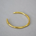 Dettaglio macro del bracciale dorato con design a linee organiche e onde irregolari - Oro