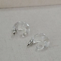 Transparent C-shaped resin hoop earrings with metal posts on cream textured fabric background - C-Shaped