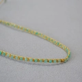 Vue macro d'un bracelet en perles de turquoise avec détails tissés en fil doré - Collier en Amazonite