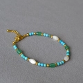 Minimalistische armband met turkoois en parelmoer kralen met goudkleurige accenten - Turkoois Met Rijstkraal