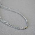 Vue macro d'un bracelet tissé main avec perles de pierre de lune et détail en or - Collier en Labradorite