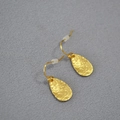 Macro detail of gold-plated leaf earrings showing handmade hammered texture and hooks - Gold