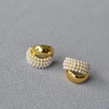 Dettaglio macro di orecchini a C dorati con metallo lucido e perle artificiali - Oro