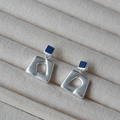 Dettaglio di orecchini geometrici in argento opaco con perni quadrati blu scuro - Argento Antico