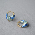 Künstlerische Spiralohrringe in Gold mit blauem Emaille-Verlauf auf grauem Stoff - Verlauf Blau