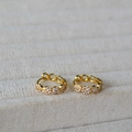 Dettaglio di orecchini a cerchio dorati con piccoli motivi floreali in zircone bianco - Oro