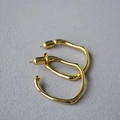 Detailed view of large irregular golden hoop earrings with high-polish metallic finish - Small / Gold