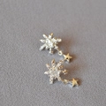 Detailopname van de 925 zilveren ster oorbellen met sneeuwvlok kristal op grijze stof - Zilver